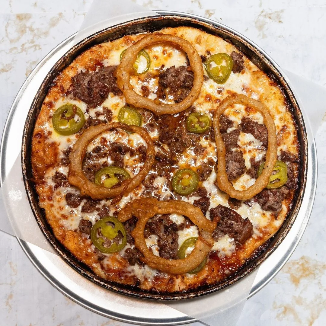 Big Tex pizza with ground beef, shaved steak, onion rings, and jalapenos on a BBQ base