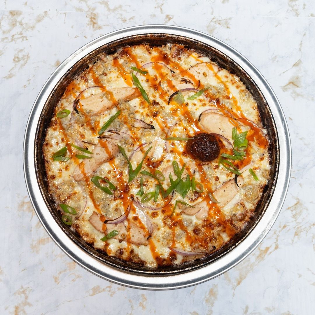 Buffalo chicken pizza with grilled chicken, blue cheese crumbles, red onion, and buffalo sauce